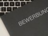 Auf einer Tastatur liegt eine schwarze Bewerbungsmappe